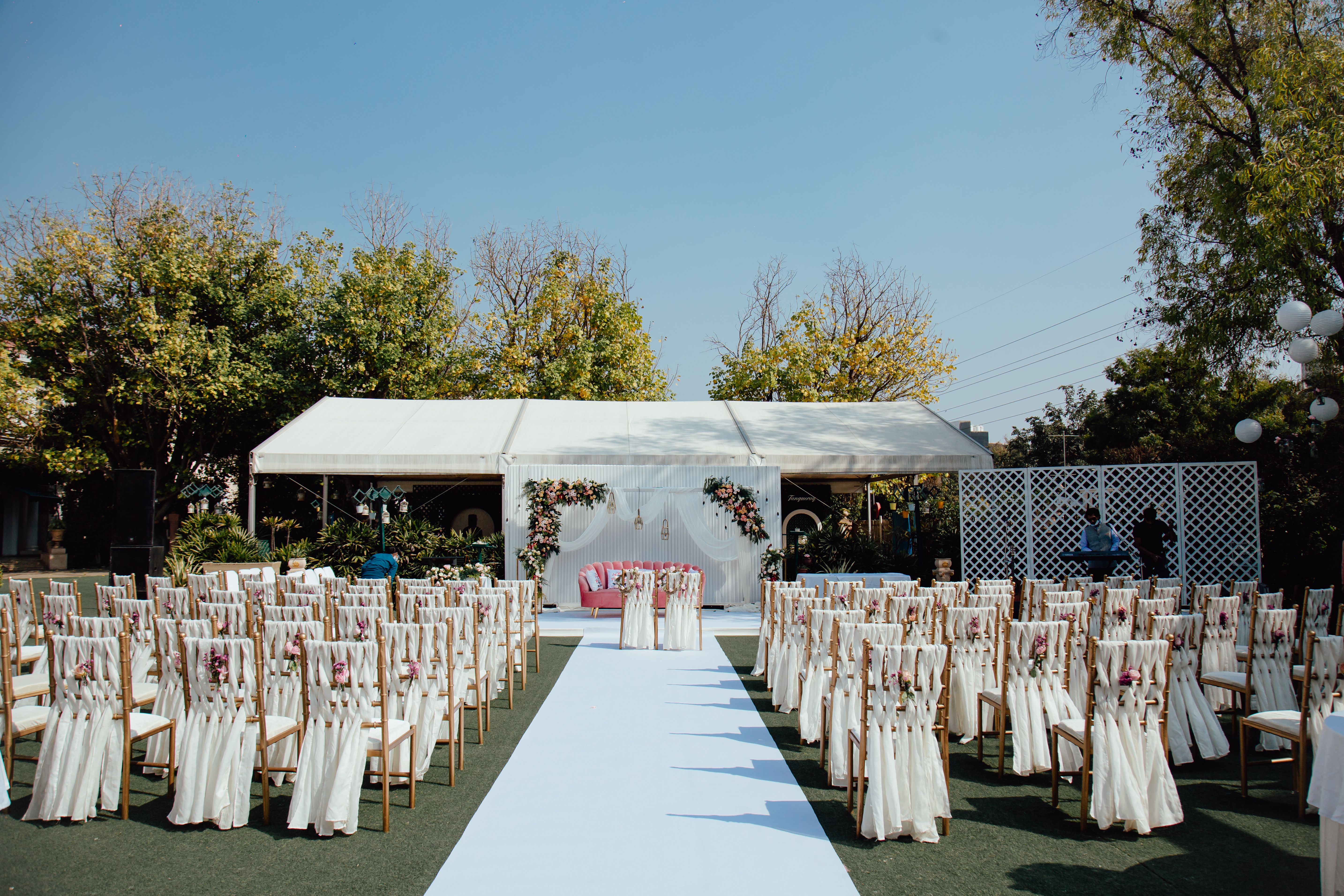 Elegant outdoor wedding ceremony with white chairs and floral arch — the kind of event where luxury portable restroom rentals make a real difference